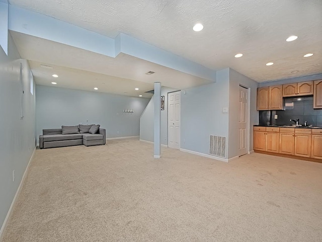 interior space featuring light carpet, a textured ceiling, visible vents, and baseboards