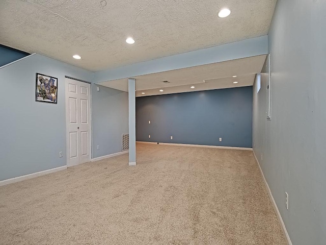 finished basement featuring carpet floors, baseboards, and a textured ceiling