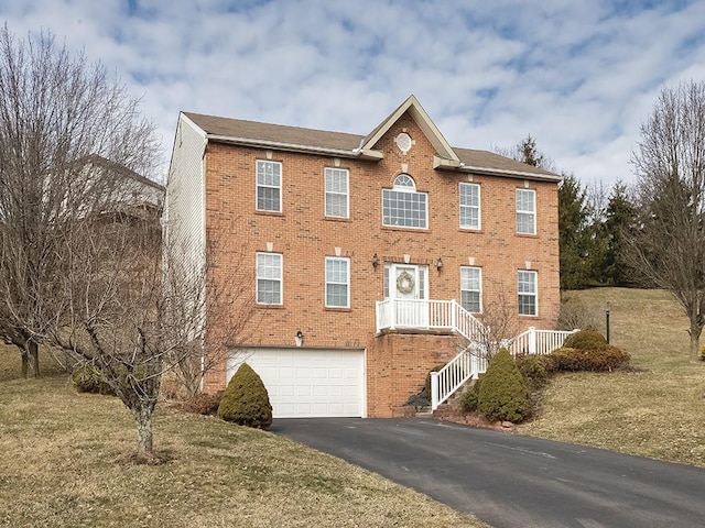 colonial house featuring an attached garage, a front lawn, aphalt driveway, and brick siding