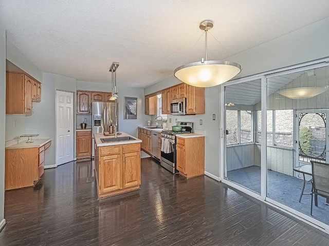 kitchen featuring stainless steel appliances, dark wood finished floors, light countertops, and a center island with sink