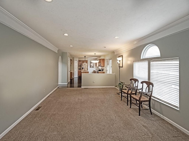 living area with baseboards, arched walkways, dark colored carpet, and crown molding