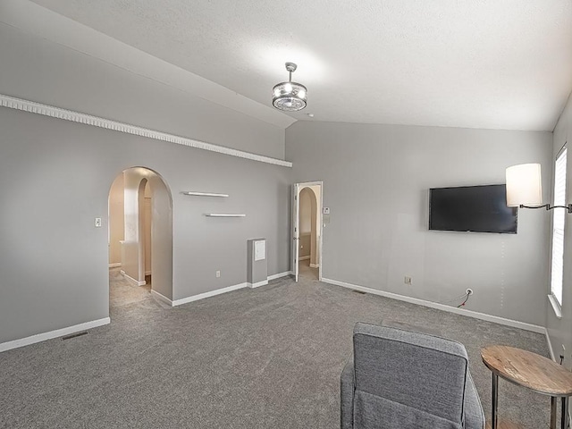 unfurnished living room featuring arched walkways, a textured ceiling, carpet flooring, baseboards, and vaulted ceiling