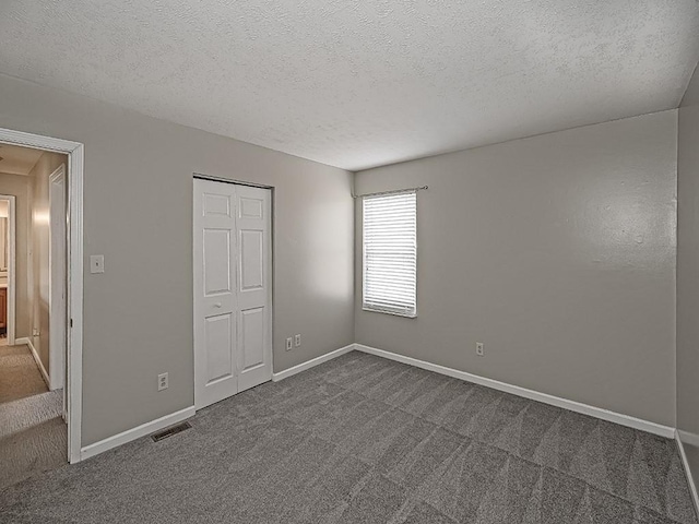 unfurnished bedroom featuring visible vents, dark carpet, and baseboards