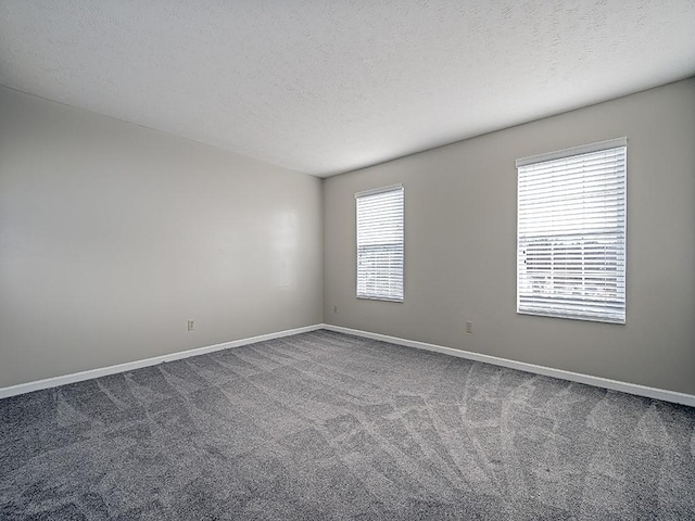 carpeted empty room with a textured ceiling and baseboards