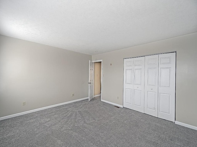 unfurnished bedroom featuring a textured ceiling, carpet floors, a closet, and baseboards