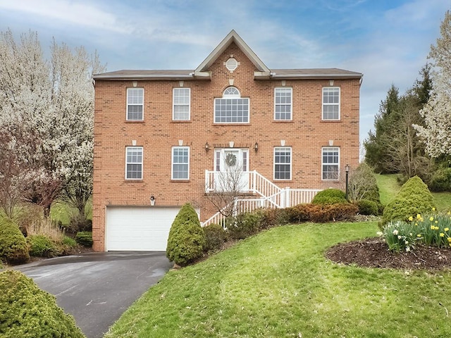 colonial-style house with brick siding, driveway, and an attached garage