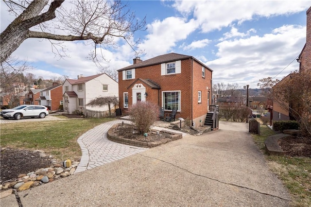 view of front of property with brick siding, concrete driveway, a residential view, a chimney, and a front yard