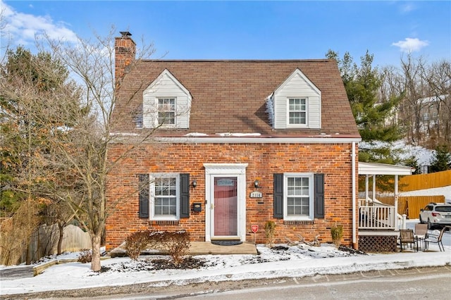 cape cod house featuring a chimney, fence, and brick siding