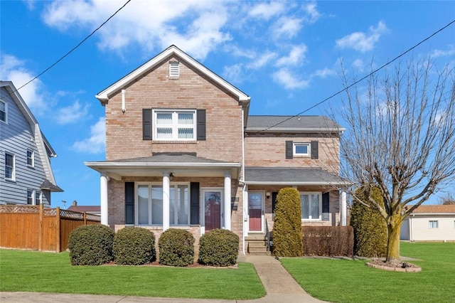 traditional home with brick siding, fence, and a front lawn