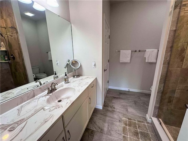 bathroom with baseboards, a shower stall, toilet, and vanity