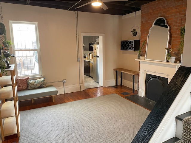 living area with a fireplace with flush hearth, baseboards, and hardwood / wood-style floors