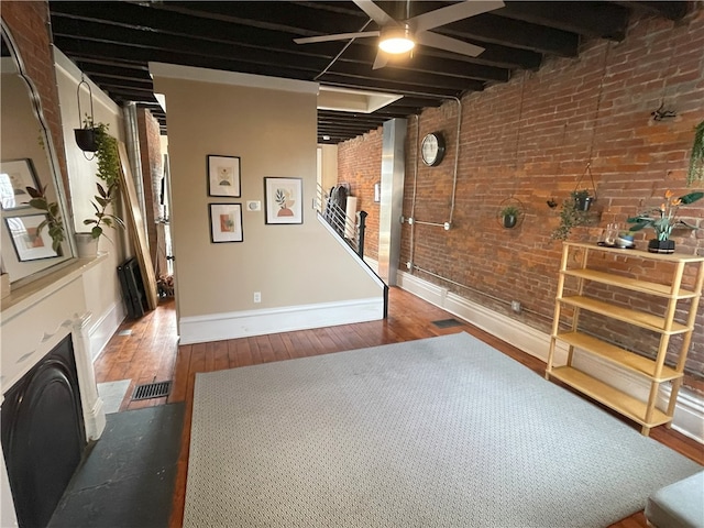 below grade area with visible vents, brick wall, hardwood / wood-style flooring, and baseboards