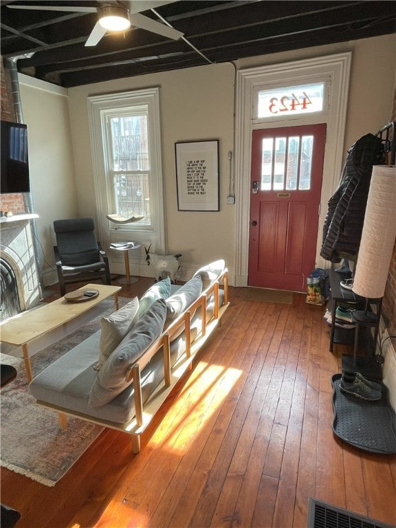 living area featuring ceiling fan, visible vents, plenty of natural light, and hardwood / wood-style flooring