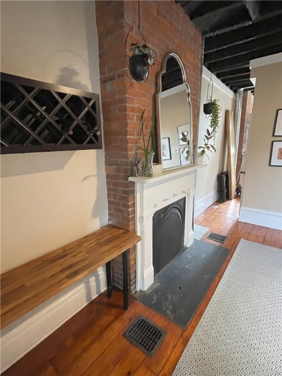 unfurnished living room with wood-type flooring, visible vents, a fireplace, and baseboards