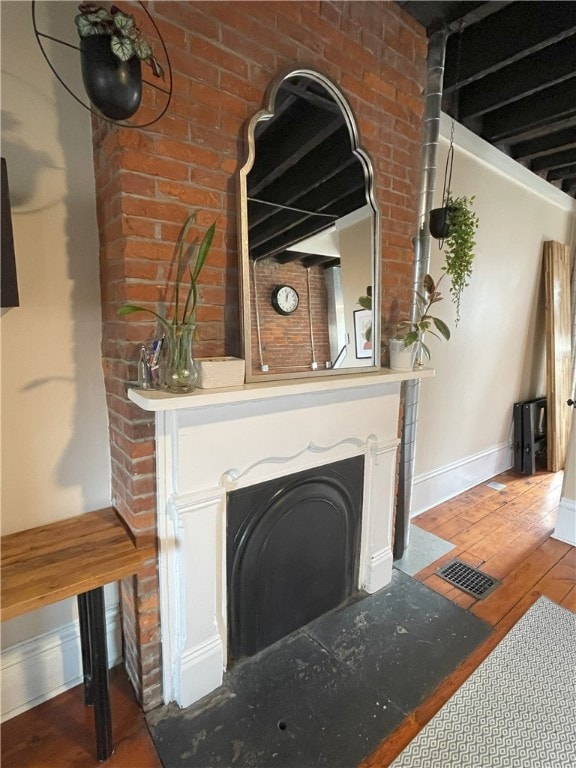 details with baseboards, a fireplace, visible vents, and wood finished floors