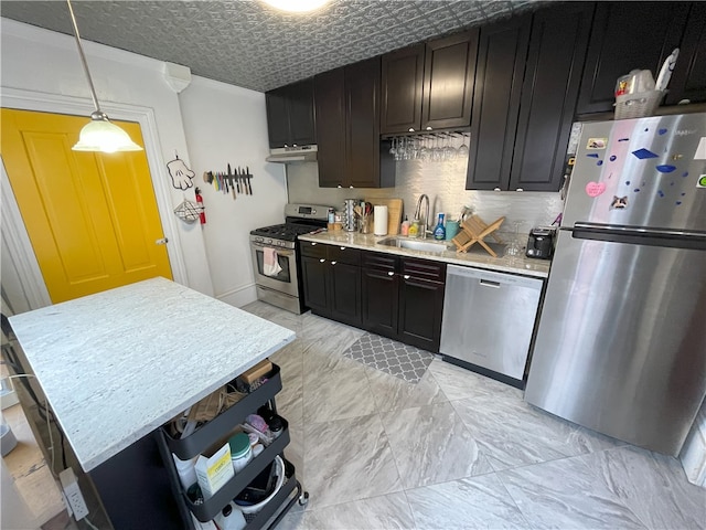 kitchen with an ornate ceiling, light countertops, decorative backsplash, appliances with stainless steel finishes, and a sink