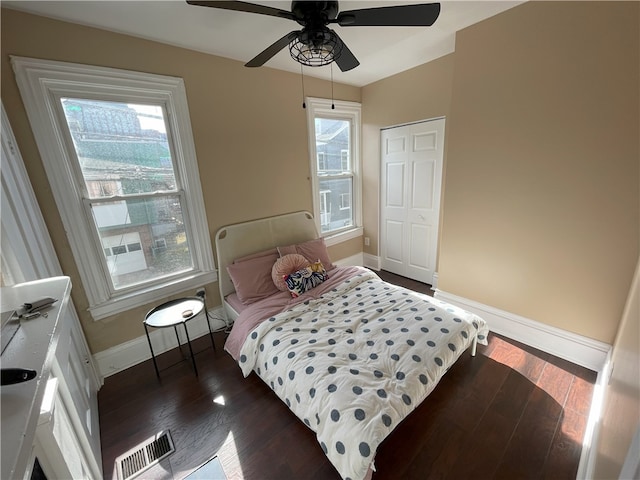 bedroom with a ceiling fan, dark wood finished floors, visible vents, and baseboards