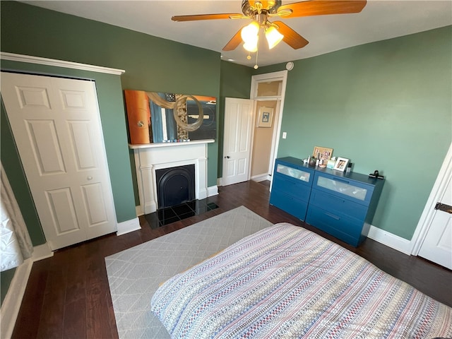 bedroom featuring ceiling fan, a fireplace, baseboards, and wood finished floors