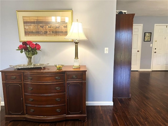 corridor with dark wood finished floors and baseboards