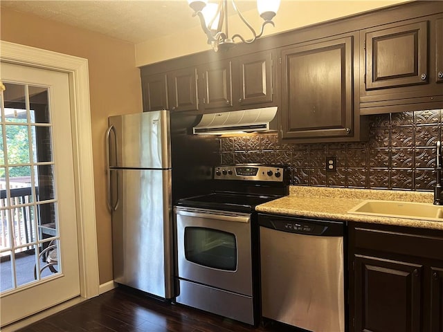 kitchen featuring dark wood-type flooring, exhaust hood, light countertops, appliances with stainless steel finishes, and decorative backsplash