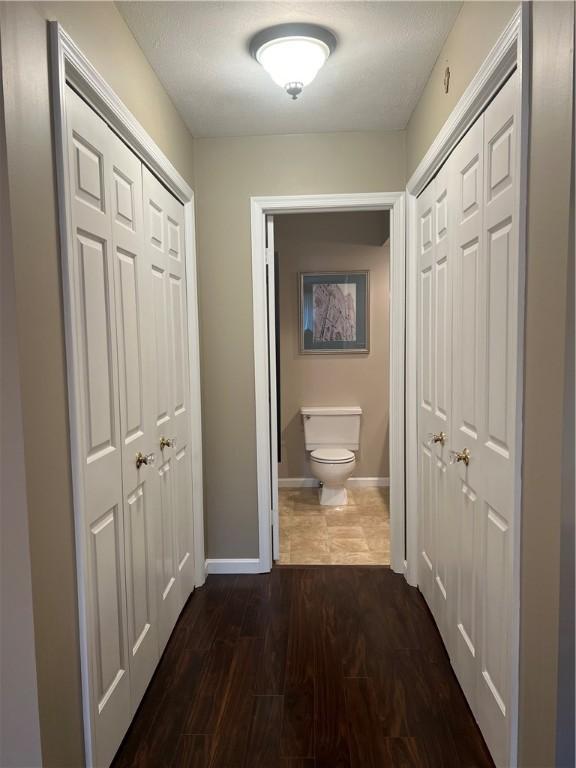 corridor with baseboards and dark wood-type flooring