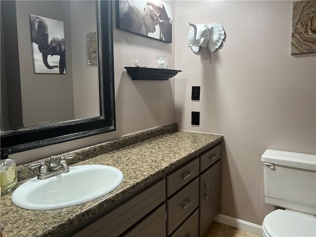 bathroom with baseboards, vanity, and toilet