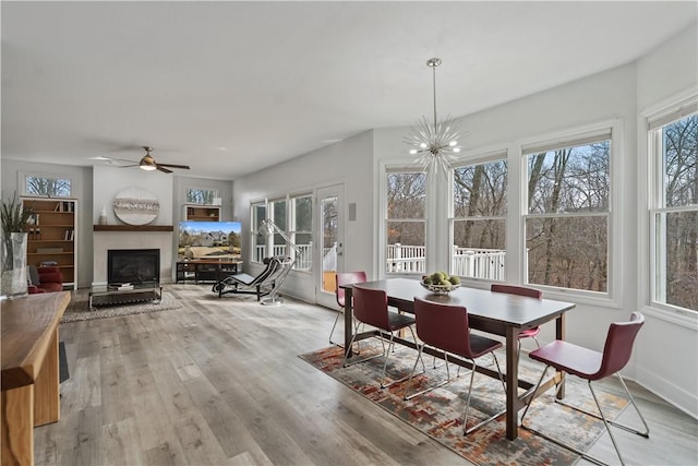 dining room featuring a wealth of natural light, a fireplace, baseboards, and wood finished floors