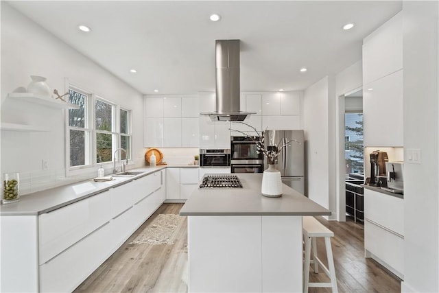 kitchen featuring appliances with stainless steel finishes, modern cabinets, a sink, and island range hood