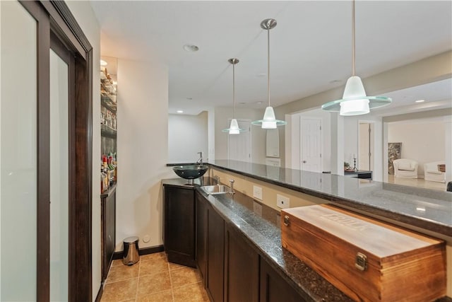 bar with decorative light fixtures, a sink, and light tile patterned flooring