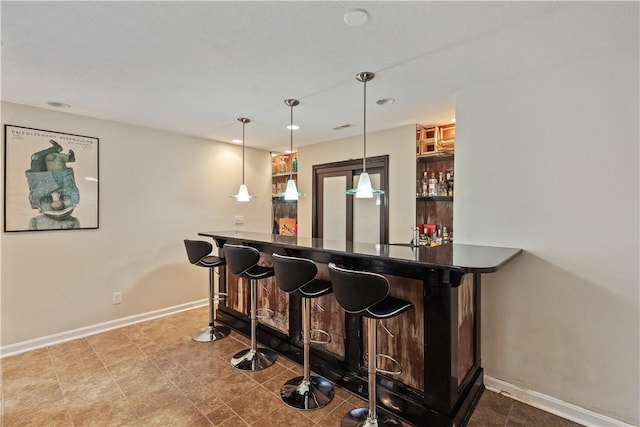 bar featuring hanging light fixtures, bar area, visible vents, and baseboards