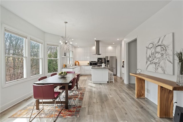 dining space with light wood-style flooring, baseboards, a notable chandelier, and recessed lighting