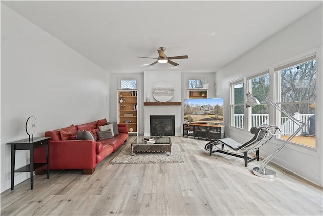 living room with ceiling fan, a fireplace, wood finished floors, and baseboards