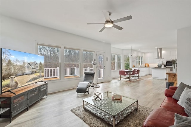 living area featuring light wood finished floors and ceiling fan with notable chandelier