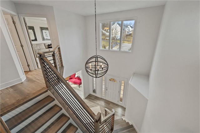 stairs with baseboards, wood finished floors, and a notable chandelier