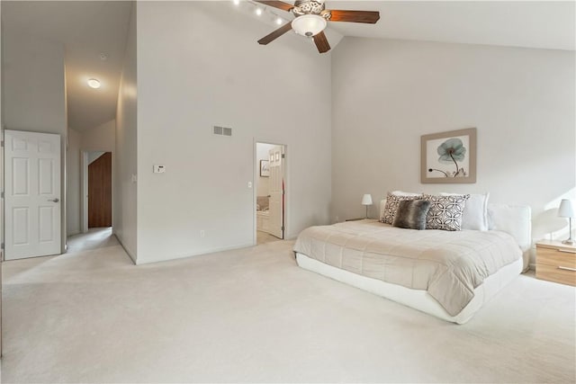 bedroom featuring light colored carpet, visible vents, ensuite bathroom, a ceiling fan, and high vaulted ceiling