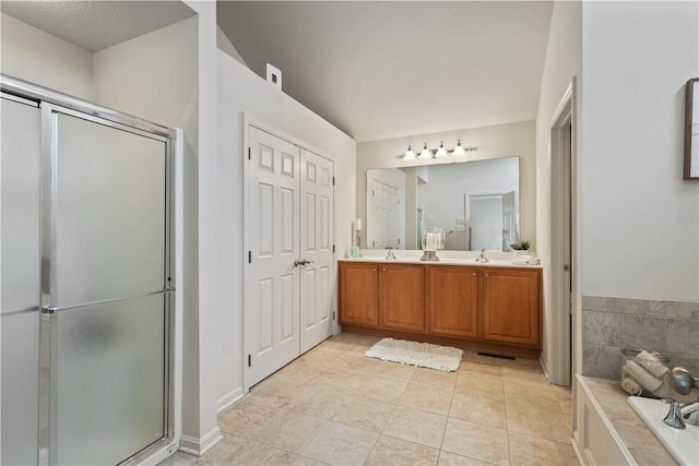 bathroom with double vanity, a shower stall, a bathtub, and tile patterned floors