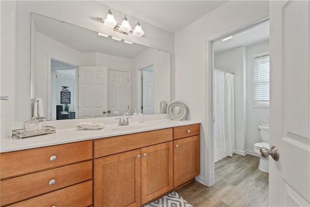 bathroom with toilet, baseboards, wood finished floors, and vanity