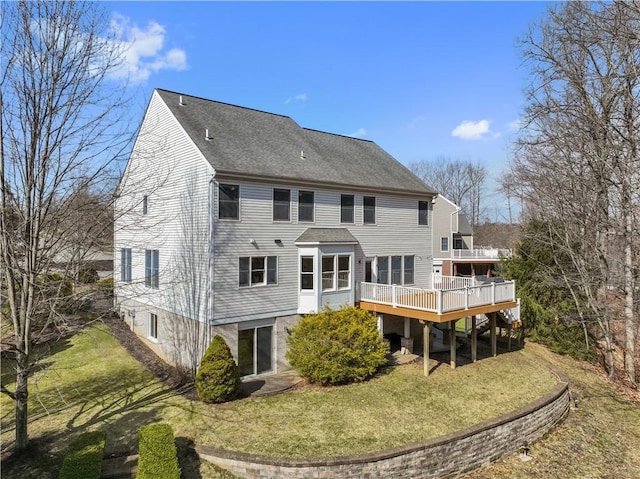 rear view of house with roof with shingles, a yard, and a wooden deck