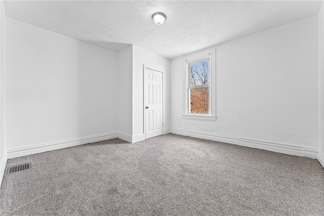 empty room featuring a textured ceiling, carpet floors, visible vents, and baseboards