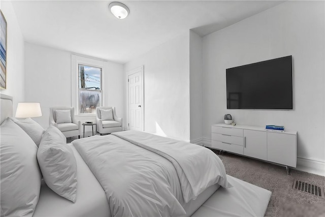 bedroom with dark carpet, visible vents, and baseboards