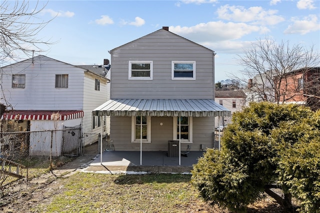 rear view of property with a gate, fence, metal roof, and a patio