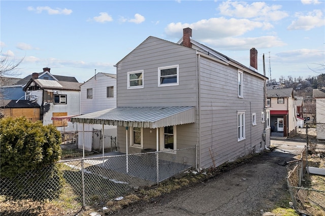 rear view of property featuring a chimney and fence