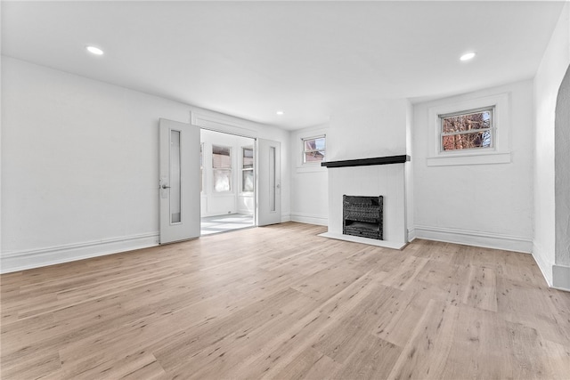 unfurnished living room featuring recessed lighting, baseboards, a fireplace, and light wood finished floors