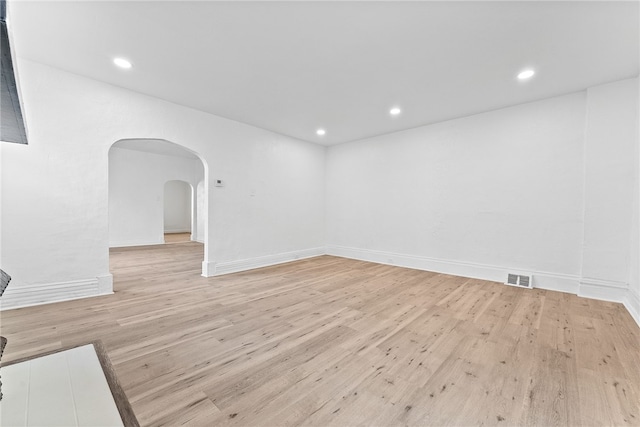 spare room with arched walkways, visible vents, light wood finished floors, and recessed lighting