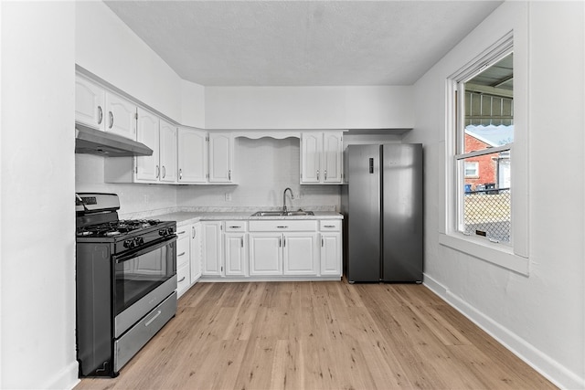 kitchen with appliances with stainless steel finishes, white cabinets, a sink, under cabinet range hood, and baseboards