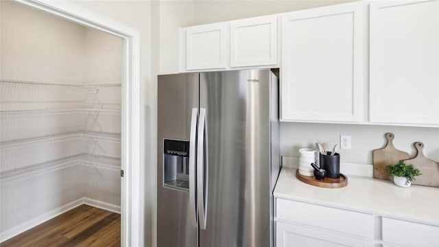 kitchen with stainless steel refrigerator with ice dispenser, light countertops, white cabinetry, and dark wood-style floors