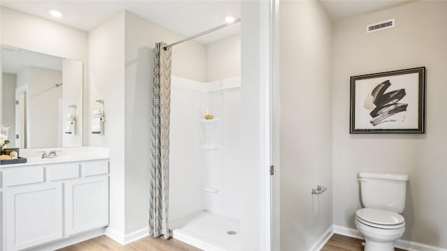 bathroom featuring toilet, wood finished floors, visible vents, a stall shower, and baseboards