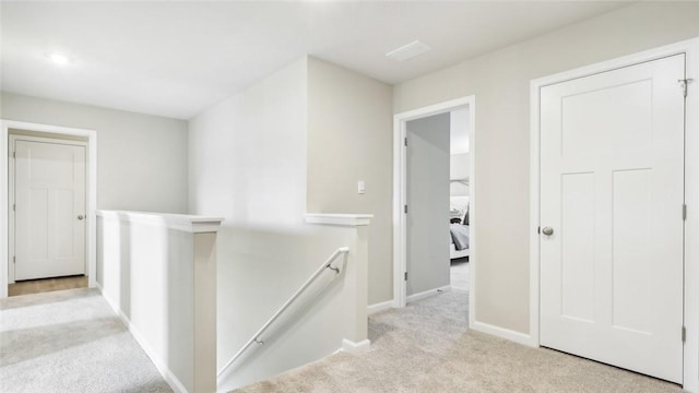 corridor with baseboards, carpet, and an upstairs landing