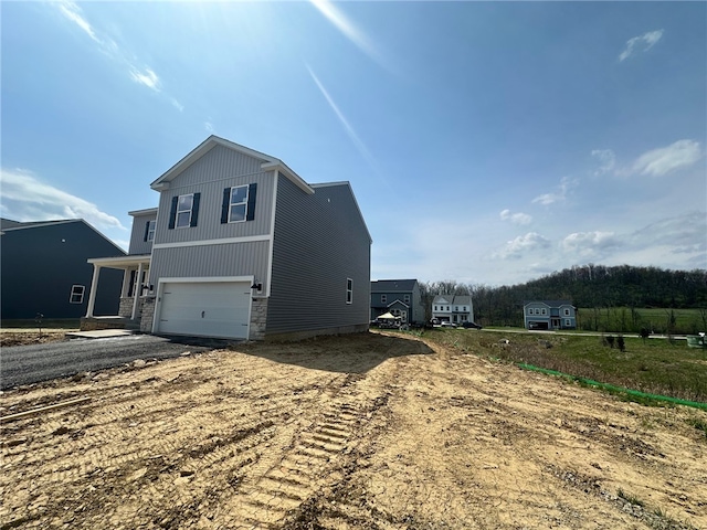 view of property exterior featuring stone siding, driveway, and a garage