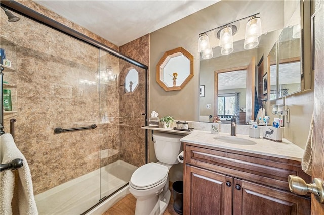 full bath with vanity, a shower stall, and toilet